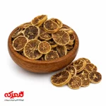 صویر دایره‌ای و منظم از اسلایس‌های لیمو خشک شده که در یک ظرف شیشه‌ای زیبا چیده شده‌اند